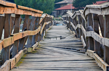 Closeup of a deformed and dilapidated wooden bridge over the riverの写真素材
