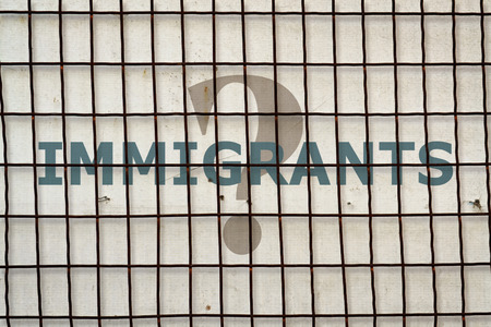 Word Immigrant written under a wire fence on vintage backgroundの写真素材