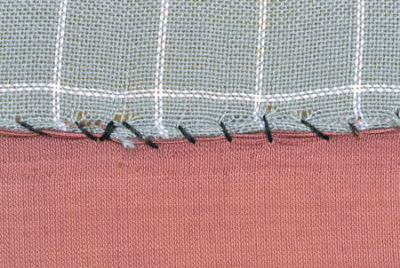 Detail of torn textile roughly repaired with a black thread