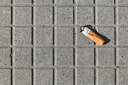 Closeup of a cigarette butt thrown on the pavementの写真素材