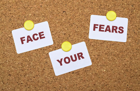 Text Face Your Fears on white stickers pinned on cork boardの写真素材
