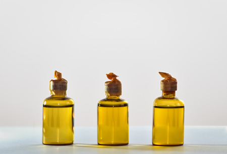 Three small yellow bottles full of chemicals on bright backgroundの写真素材