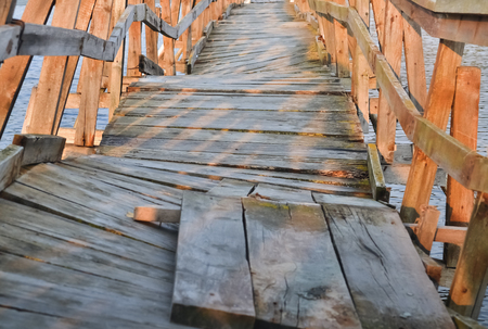 Detail of a deformed wooden bridge over a small riverの写真素材