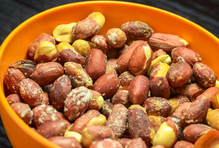 Orange plastic bowl full of roasted peanutsの写真素材