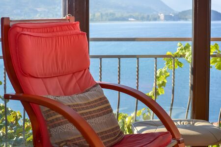 Detail of a red wooden armchair by the window and beautiful panoramic view to the lakeの写真素材