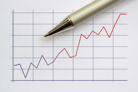 Two color broken line graph and a pen on bright backgroundの写真素材