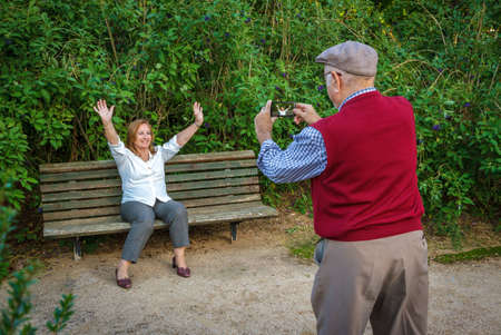 Senior couple in love taking pictures in a park. They are 75 years oldの写真素材
