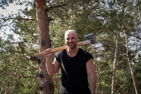One handsome strong stylish man holding wooden axe in forest outdoorの写真素材