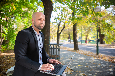 Young business man with laptop in the parkの写真素材