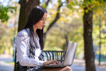 Young business woman with laptop in the parkの写真素材