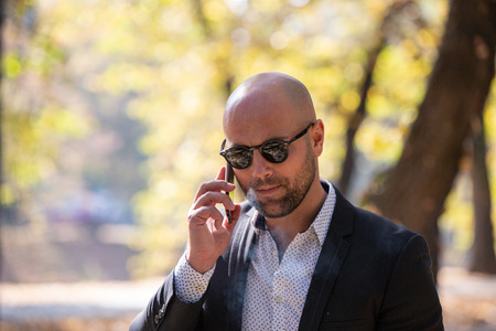 A handsome young businessman talking on his phone in the parkの写真素材