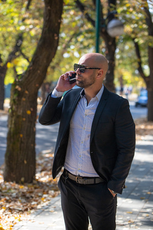 A handsome young businessman talking on his phone in the parkの写真素材