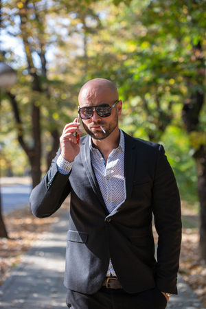 A handsome young businessman talking on his phone in the parkの写真素材
