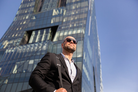 Handsome elegant businessman with sunglasses in front of office buildingの写真素材