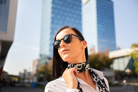 Confident business girl with sunglasses in front of office buildingの写真素材