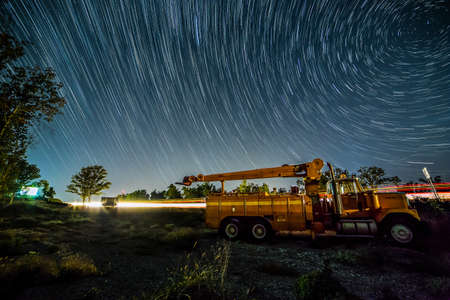 Abandoned Commerical Veichle sits on the side of the highway collecting rust, ast the stars spin in the night sky の写真素材