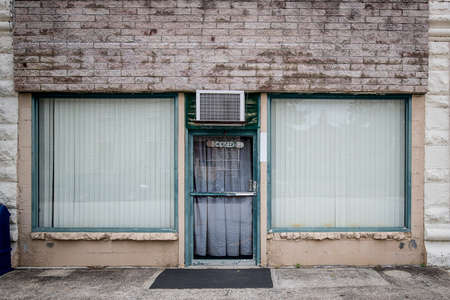 An abandoned store front is empty an neglected with a closed sign on the front door.の写真素材