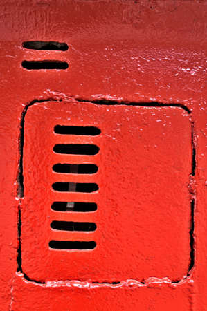 Old metal door with vents, painted with red paintの写真素材