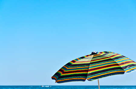 Colorful umbrella against the blue sky and the sea horizonの写真素材