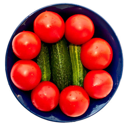 Blue salad bowl with fresh tomatoes and cucumbers, top view. Isolated on white.の写真素材