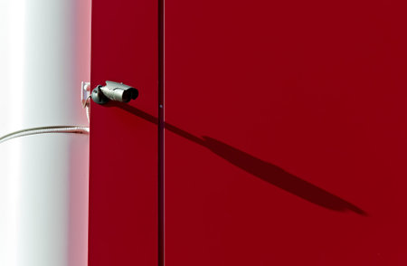 High-tech infrared security camera on the background of a red wall.の写真素材