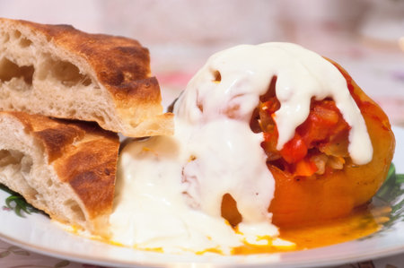 Stuffed peppers under sour cream, with pieces of pita. On a plate. Close-up.の写真素材
