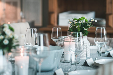 Laid wooden table with tableware, glasses and flowers