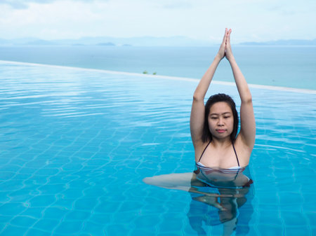 beautiful professional asian woman practice aqua yoga water therapy tree pose balance in swimming...