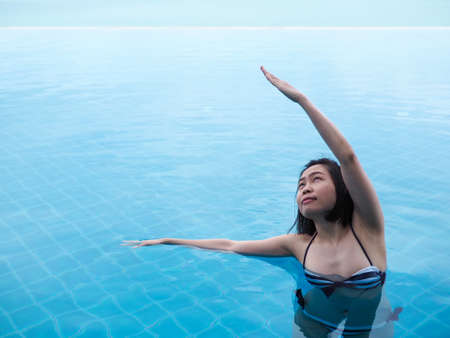 beautiful professional asian woman practice aqua yoga water therapy side bend pose balance in swimming pool body mind spirit spiritual healingの写真素材