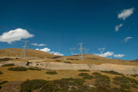 Colorful landscape with beautiful mountain road with high voltage electrical pole structure and blue sky in chinaの写真素材