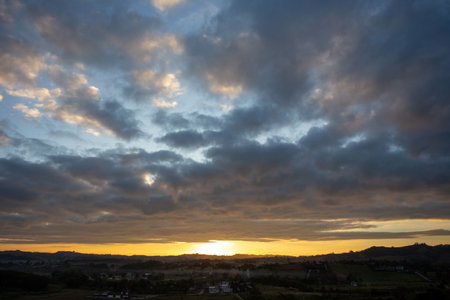 Morning view at morning sunrise, clouds in orange crimson colors. Silhouettes of houses roofs, trees, and a monastery on the hill. Colorful scenery skyline background.の写真素材