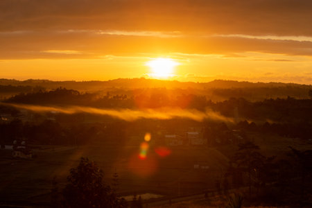 Morning view at morning sunrise, clouds in orange crimson colors. Silhouettes of houses roofs, trees, and a monastery on the hill. Colorful scenery skyline background.の写真素材