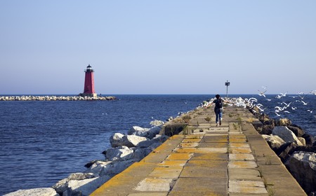Tourist running on the pier and scaring the birds away.の写真素材