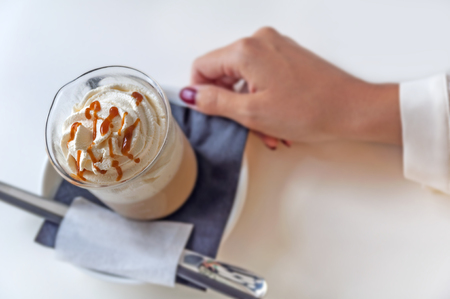 Cup of a fresh caramel latte with whipped cream in coffee shop on table 1の写真素材