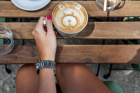 Female hands holding Latte art with bear shape, coffee cup on tableの写真素材