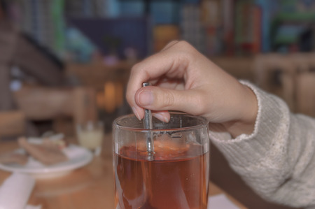Girl sitting in restaurant and mix glass of red teaの写真素材