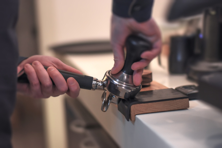 Professional barista tamping espresso spoon and making perfect coffee drinkの写真素材