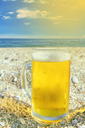 Photo of cold beer bottle in the sand on the beachの写真素材