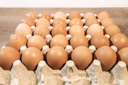 A lot of eggs in carton package on a wooden table ready for baking