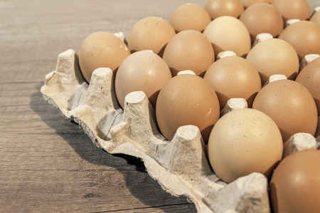 Eggs in carton package on a wooden table ready for cookingの写真素材