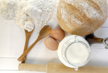 Fresh baked bread and ingredients for cooking, eggs, milk, flourの写真素材
