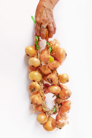 Woman holding golden onions in closeup isolated on whiteの写真素材