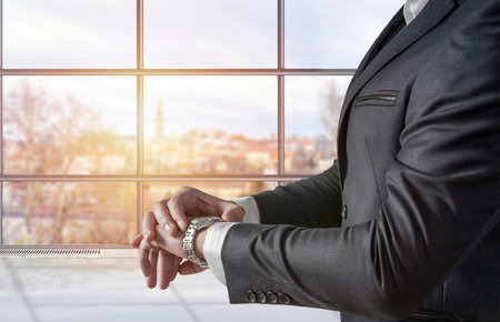 Businessman looking at his watch and watching the time in the office