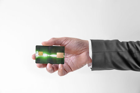 Man in elegant custom suit holding green bank credit plastic card on white background
