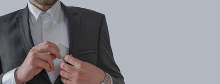 Businessman pulls out white card from the pocket of business suit with copyspaceの写真素材