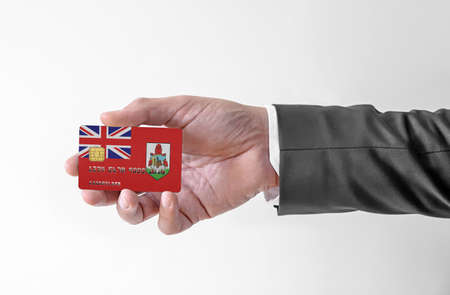 Bank credit plastic card with flag of Bermuda holding man in elegant suitの写真素材