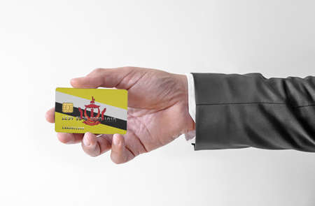 Bank credit plastic card with flag of Brunei holding man in elegant suitの写真素材