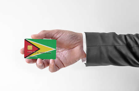 Bank credit plastic card with flag of Guyana holding man in elegant suitの写真素材