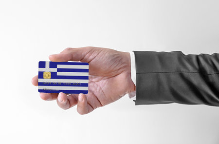 Bank credit plastic card with flag of Greece holding man in elegant suitの写真素材