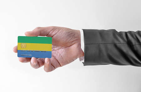 Bank credit plastic card with flag of Gabon holding man in elegant suitの写真素材